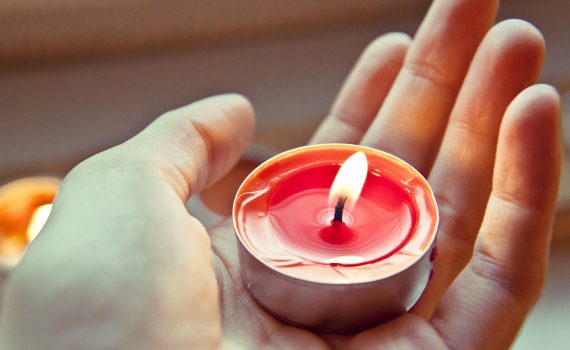 Main tenant une bougie rouge orangée